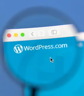 A magnifying glass focused on a computer screen displaying the WordPress.com logo and web address inside a browser window