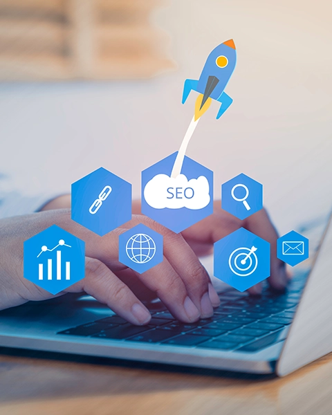 A person typing on a laptop with icons representing SEO, analytics, and digital marketing goals surrounding a rocket taking off.